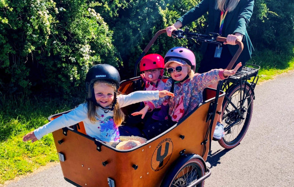 El-lastesykkel med tre barn på lasteplanet pluss syklist.