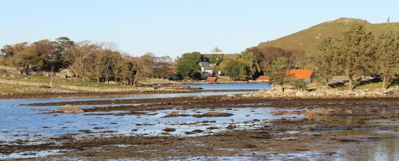 Utstein Kloster sett over Klostervågen ved fjære sjø