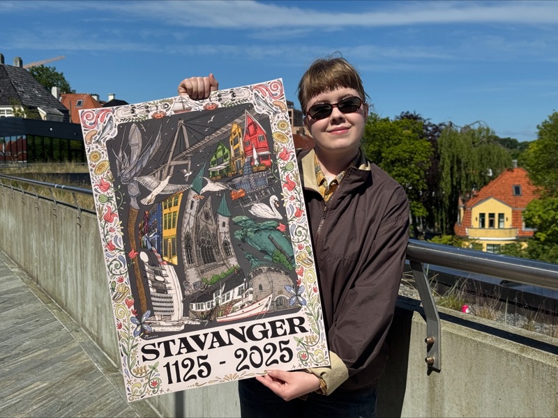 Kunstner Johanna Warberg smiler fornøyd med Jubileumsplakaten 2025 i hånden. 