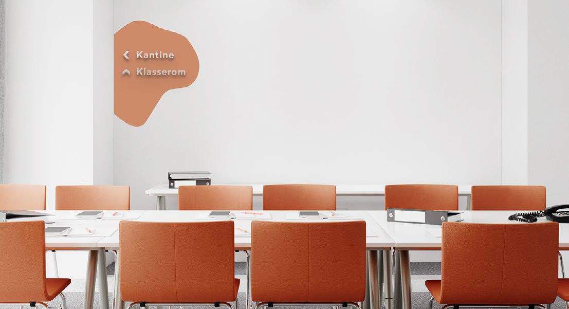 Oransje skilt med øyform, i et skolemiljø med bord og stoler