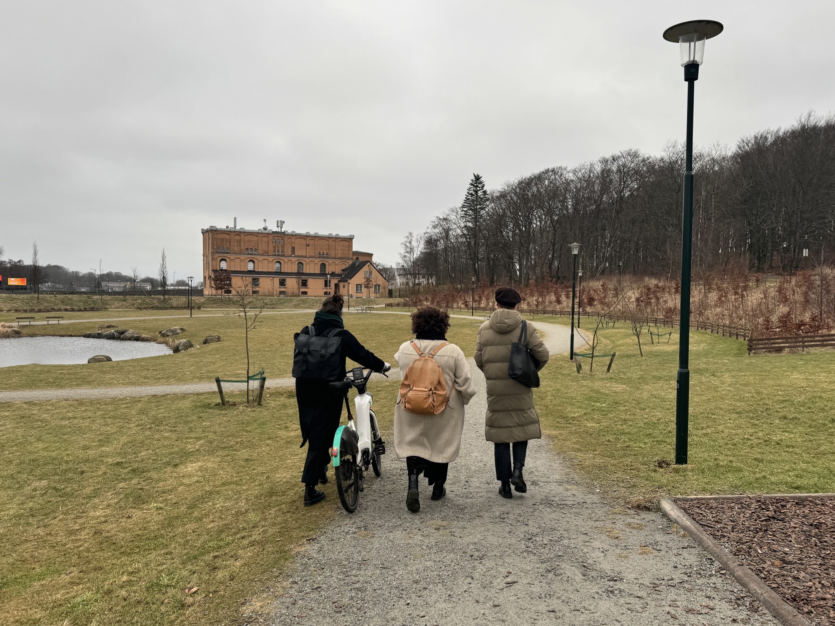 Tre personer spaserer ved mosvannet