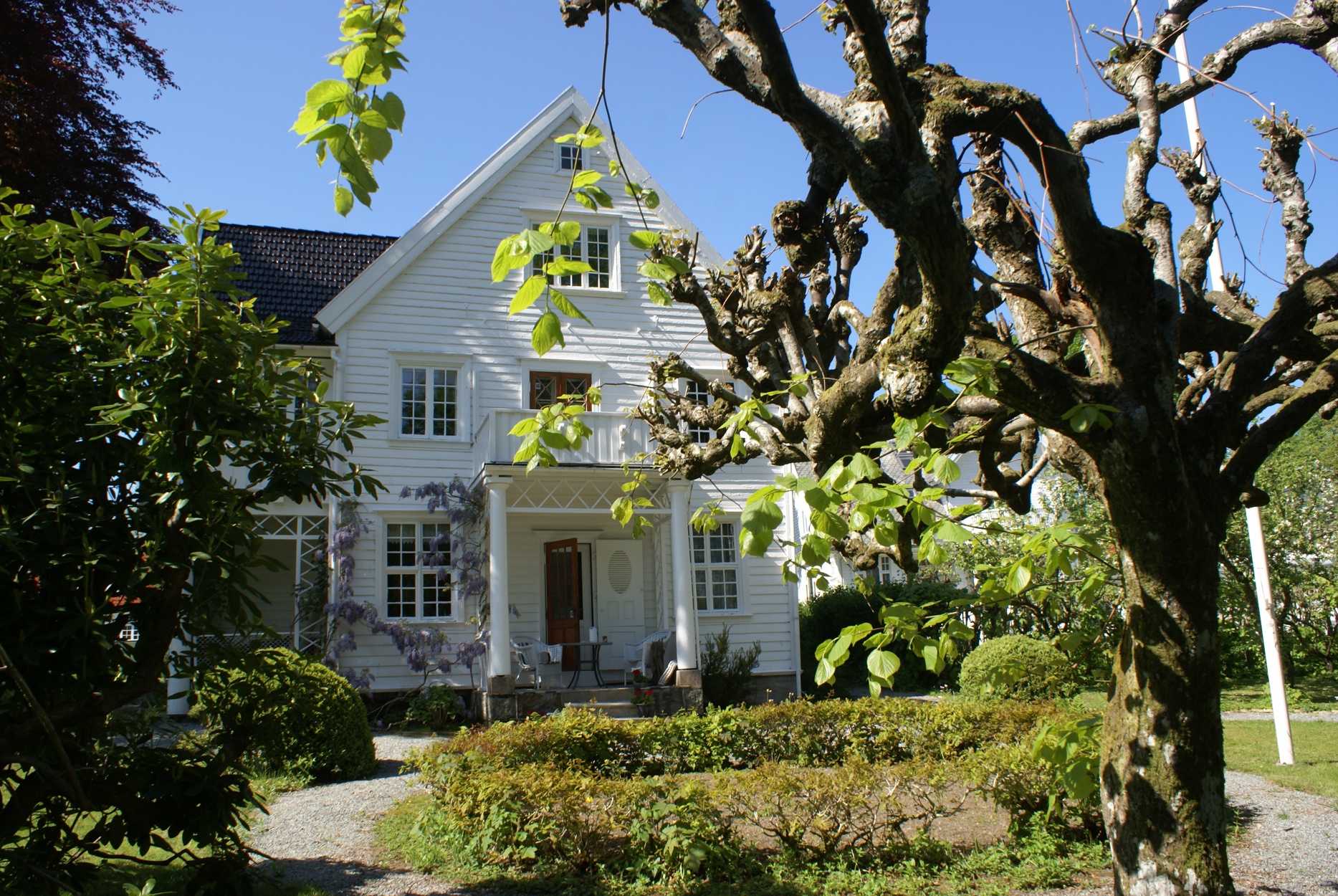 Hvitt hus i forsommerhage.