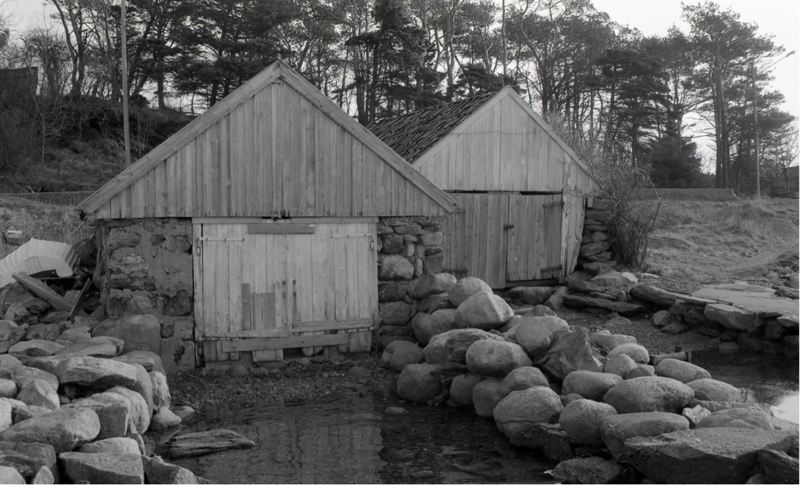 To tradisjonelle naust, med steinvegger og båtstøer foran.