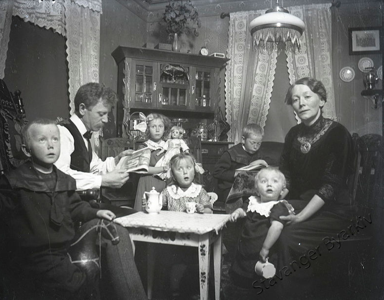 Familie med fem barn (og en dukke) i gamle dager. Alle ungene ser litt øvegidde ut. Foto: Stavanger byarkiv