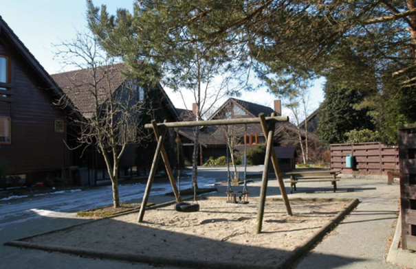 Lekeplass med dissestativ og trær.