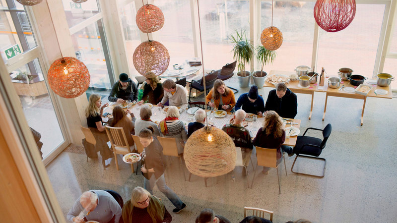 Folk som sitter rundt et langbord og spiser.