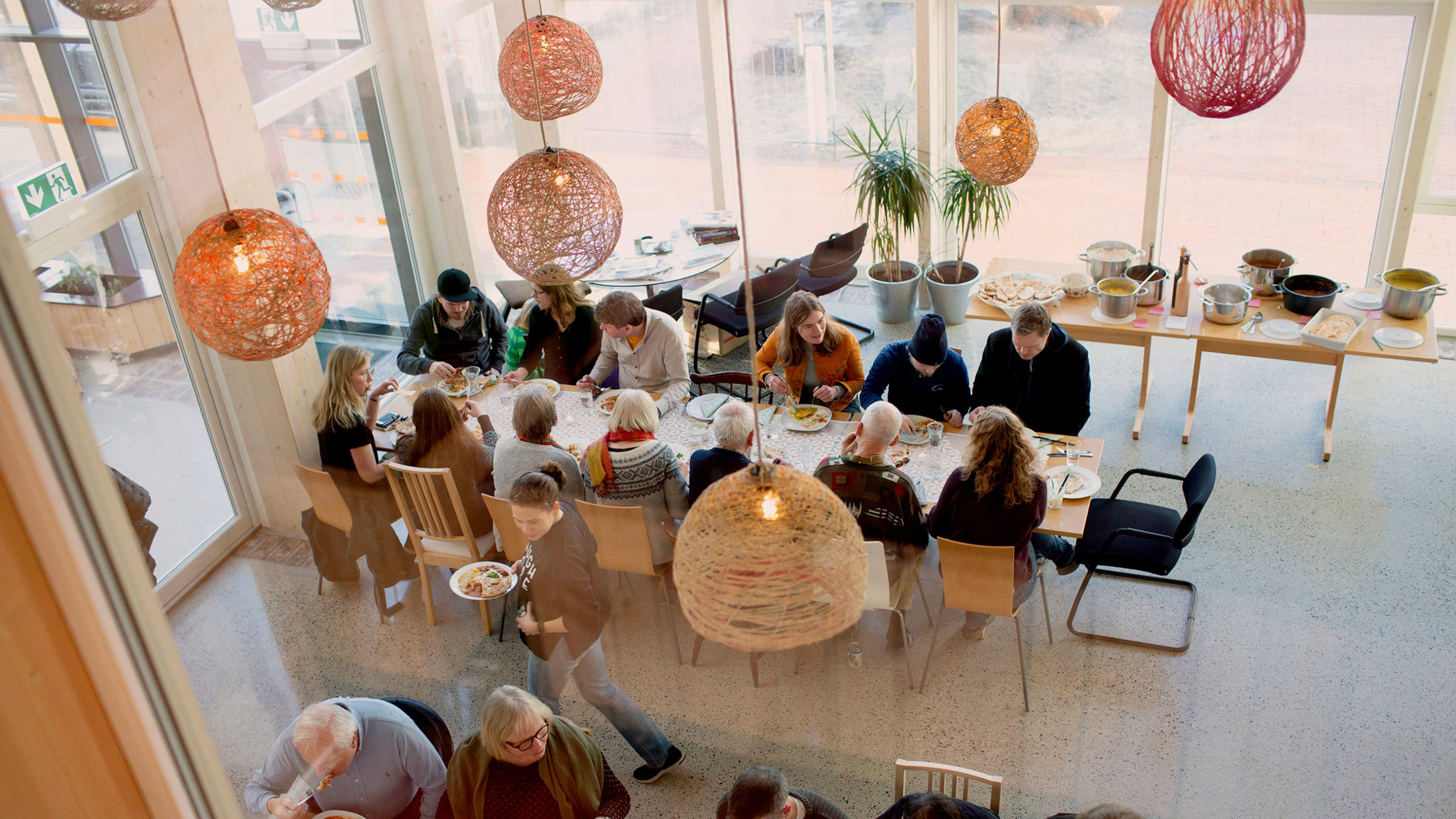 Folk som sitter rundt et langbord og spiser.