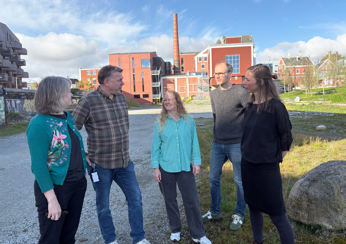 Utvidelsen av parken foran Tou er et samarbeid mellom kommunen og kulturinstitusjonen, og skal skje på klimaets premisser. Fra venstre: seksjonssjef Else Dybkjær fra Stavanger kommune, daglig leder på Tou Per Arne Alstad, FutureBuilt-prosjektleder Heather Bergsland, teknisk ansvarlig Ole Reidar Gudmestad fra Tou og landskapsarkitekt Elin Henricson fra Stavanger kommune. Fem personer med kulturbygget Tou i bakgrunnen.