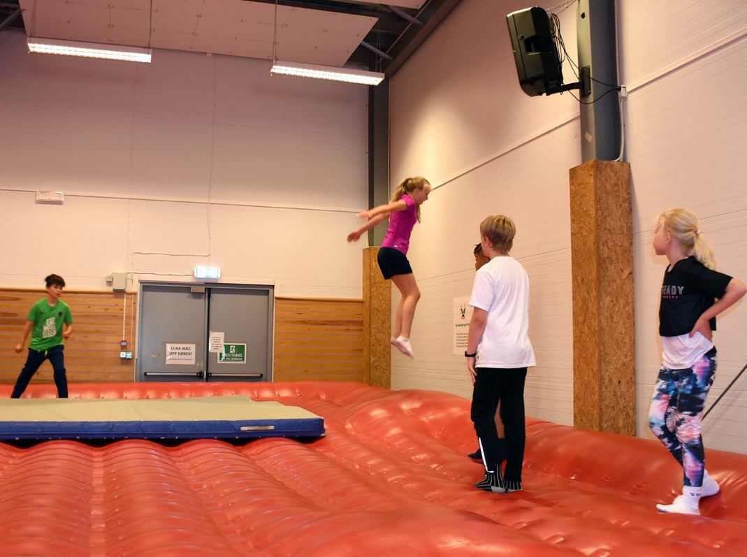 Barn hopper på en stor oppblåst, oransje vegg-til-vegg-pute