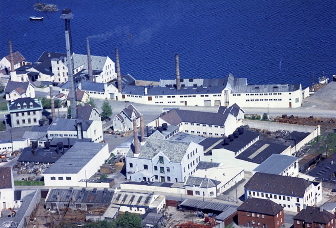 Tinnfabrikken, med sine lavere hvite fabrikkbygninger og 58 meter høye, spinkle tårn.