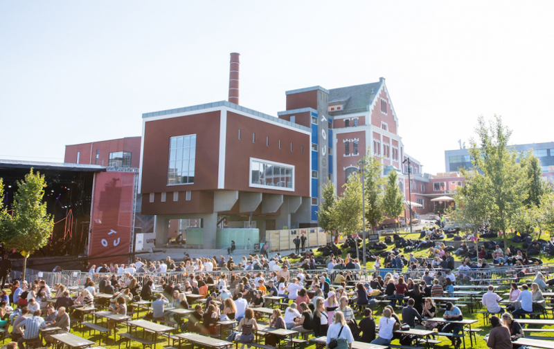 Mange folk sitter utenfor Tou Scene i sola