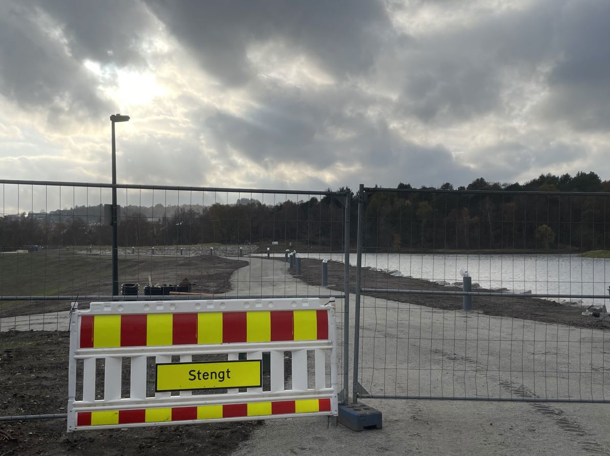 ny trusti ved vann er stengt med skilt og anleggsgjerde