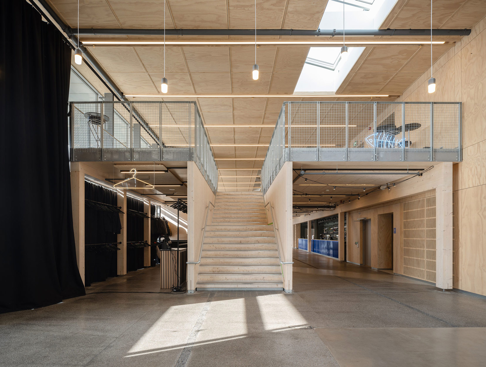 Bildet inne, med en trapp som leder opp til møssaninen. Romløsningen har en tiltalende romsekvens som danner flere mindre soner og får det langsmale rommet til å fungere godt i de mange ulike brukssituasjonene.