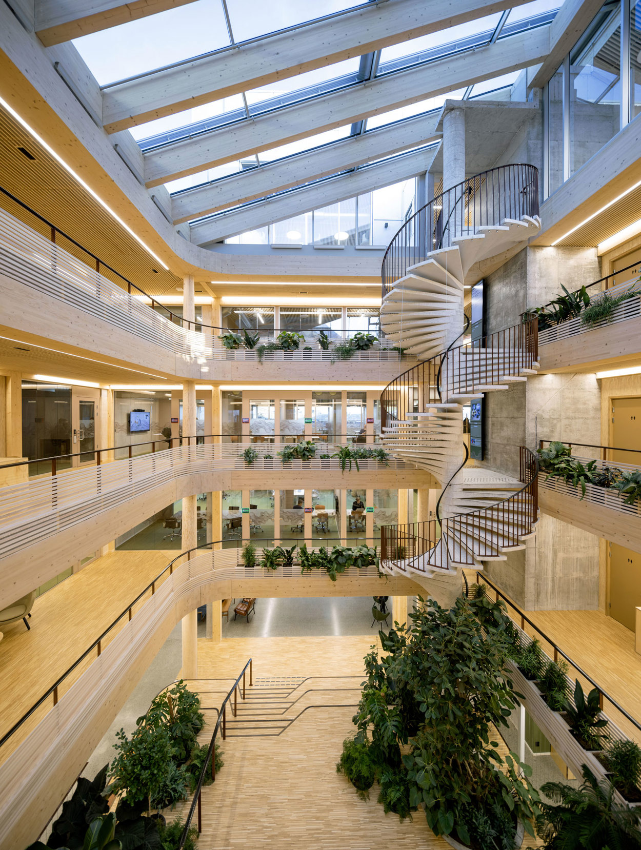 Bilde av atriet der man ser alle etasjene og glasstaket på toppen. Sammen med byggets planløsning har arkitektene utviklet prinsipper for bruken som stimulerer delingskultur og at organisasjoner kan ha organisk vekst. Byggets attraktive romlighet gjør det også til ettertraktet møteplass for gjestende arrangementer.