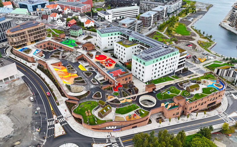 Dronebilde av hele skole- og barnehagekvartalet med sykehjemmet i samme kvartal, og nyere boligblokker i området rundt. 