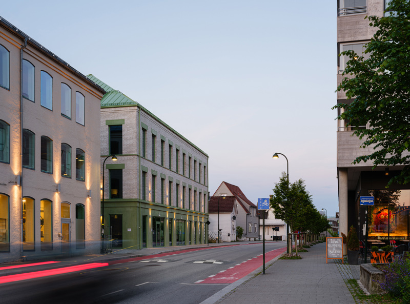 Gatebilde med treetasjers murbygg på venstre side av gata - et gammelt til venstre og et nytt til høyre.