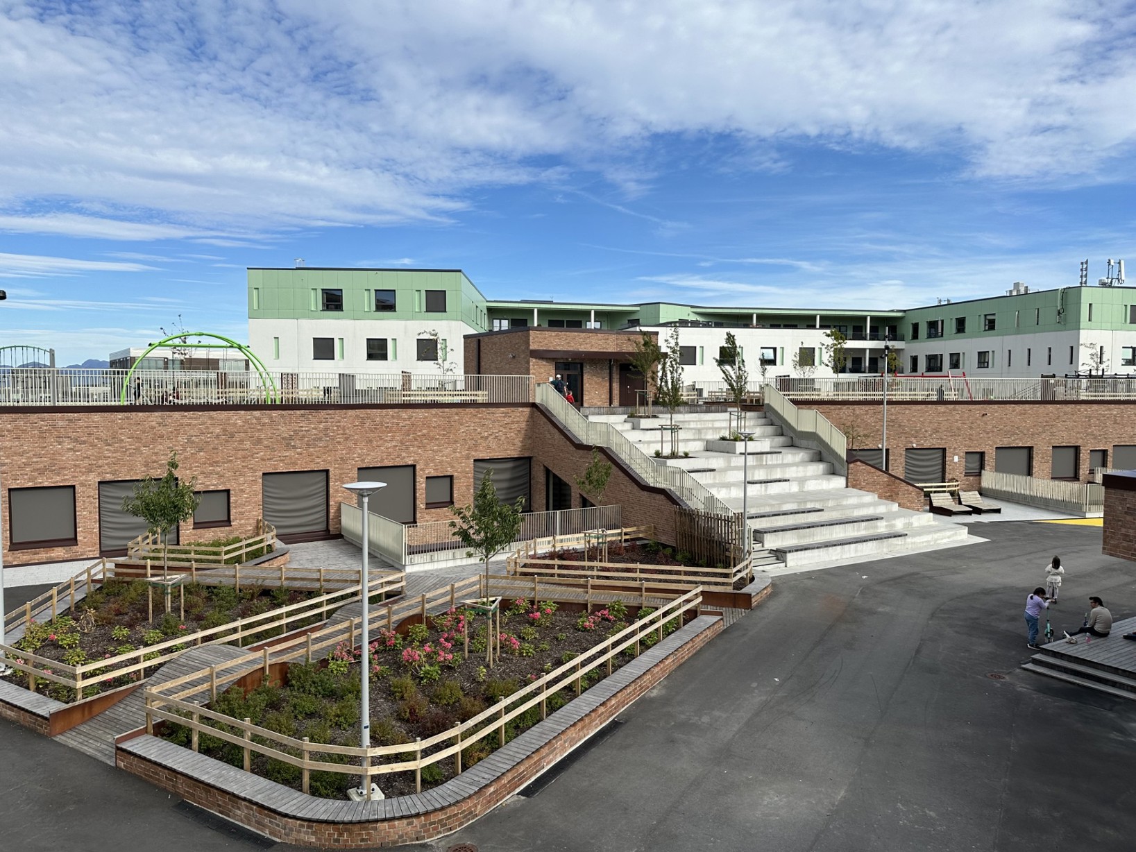 Skolegård med amfi i trappene, asfalt på bakken og vegger kledd med tegl.