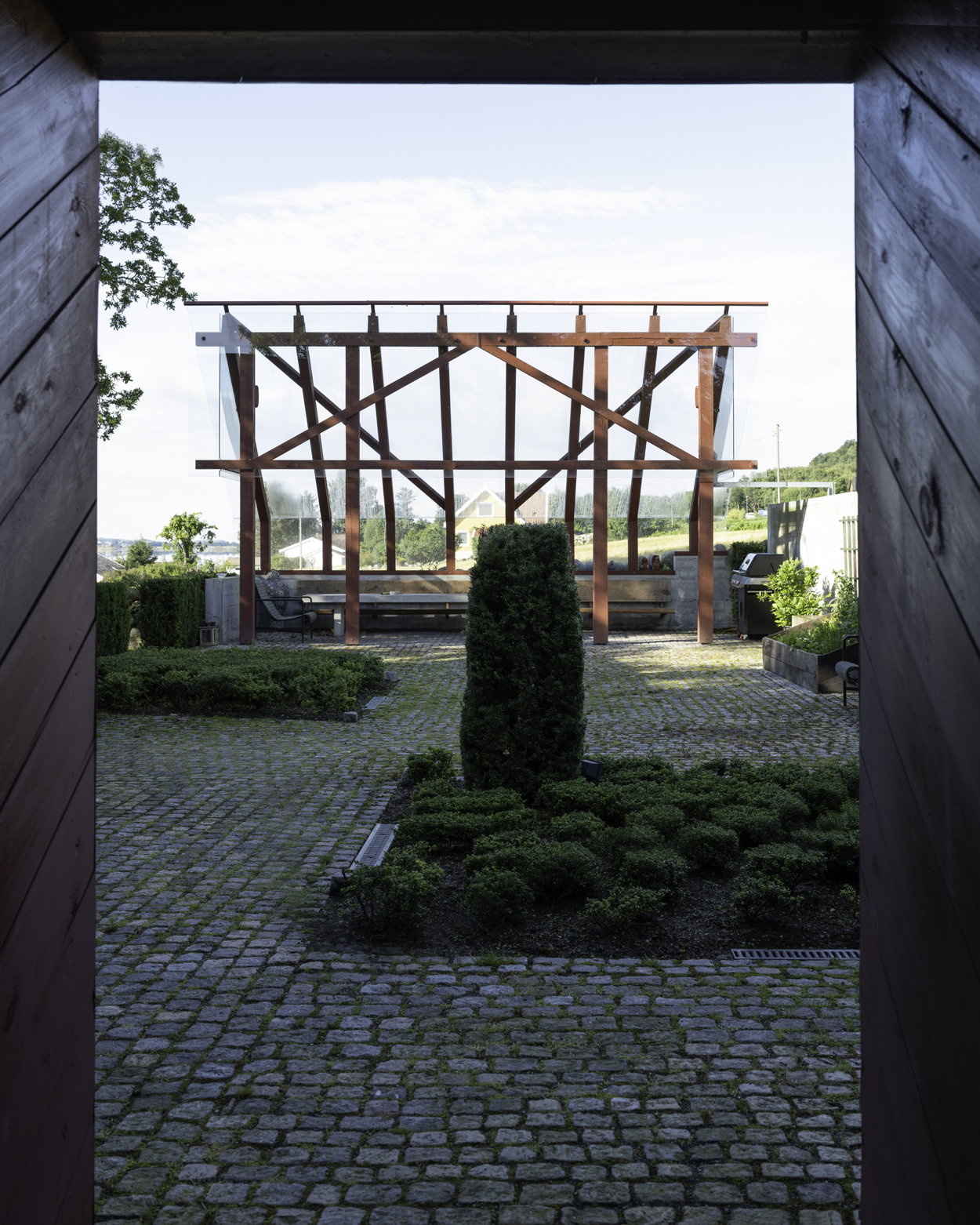 Gårdsrommet mellom det gamle huset og det nye tilbygget. I enden ser vi en pergola med glassvegger.