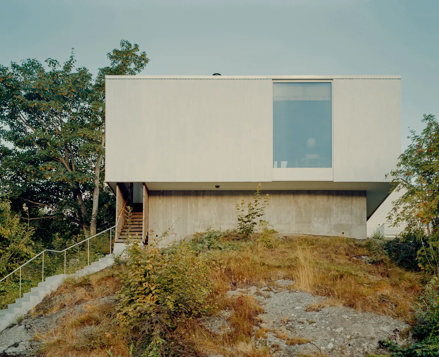 Huset sett utenfra, og lang trapp opp fra fortauet. Ett vindu i fasaden.