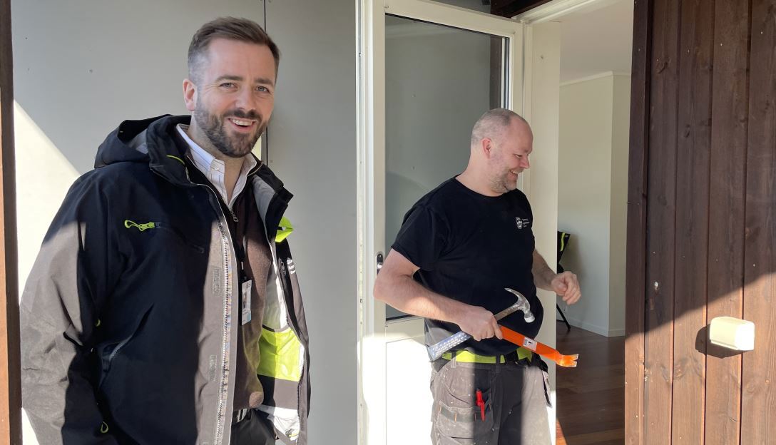 Jonas Meling (til venstre) leder boligbygg-seksjonen i kommunen, som kjøper opp kommunale boliger. Kjetil Kaltveit setter boliger i stand til nye leietakere, her ved en bolig på Madla, en av bydelene med relativt få kommunale boliger. Jonas Meling og Kjetil Kaltveit står ute på terassen til en nyere bolig.
