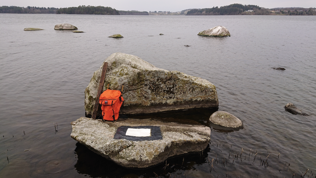 Signalmerke (hvit firkant med svart ramme) på en stein i sjøen