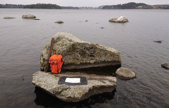 Signalmerke (hvit firkant med svart ramme) på en stein i sjøen
