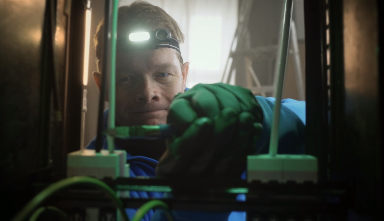 Elektriker som titter inn i sikringsskap. Skjermbilde fra promoteringsfilm for Tettpå-kampanjen 2022