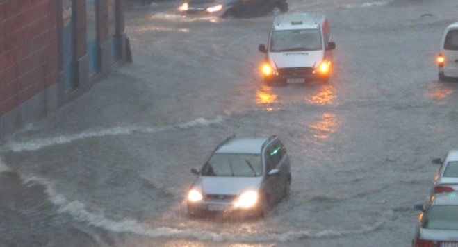 Biler kjører gjennom et lyskryss i København, og det er vann opp over hjulene etter ekstrem nedbør.