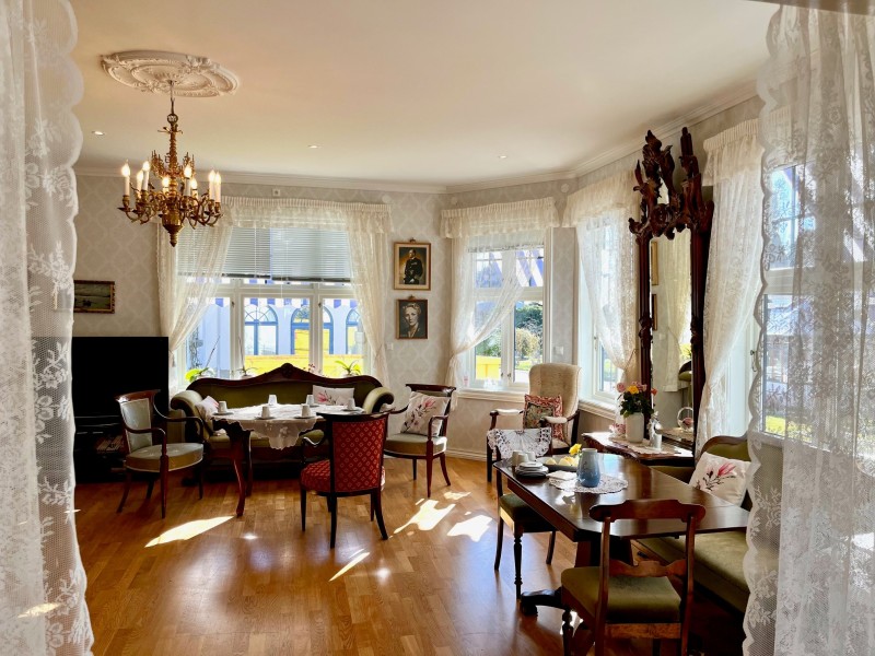 Bildet viser en fin stue med gamle flotte møbler og bilder på veggene.