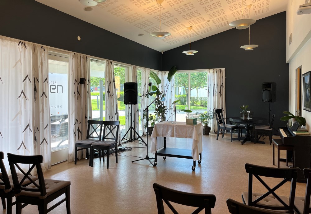 Bildet viser aktivitetsrommet. Stoler og bord, høyt under taket med hvite vegger med bilder.