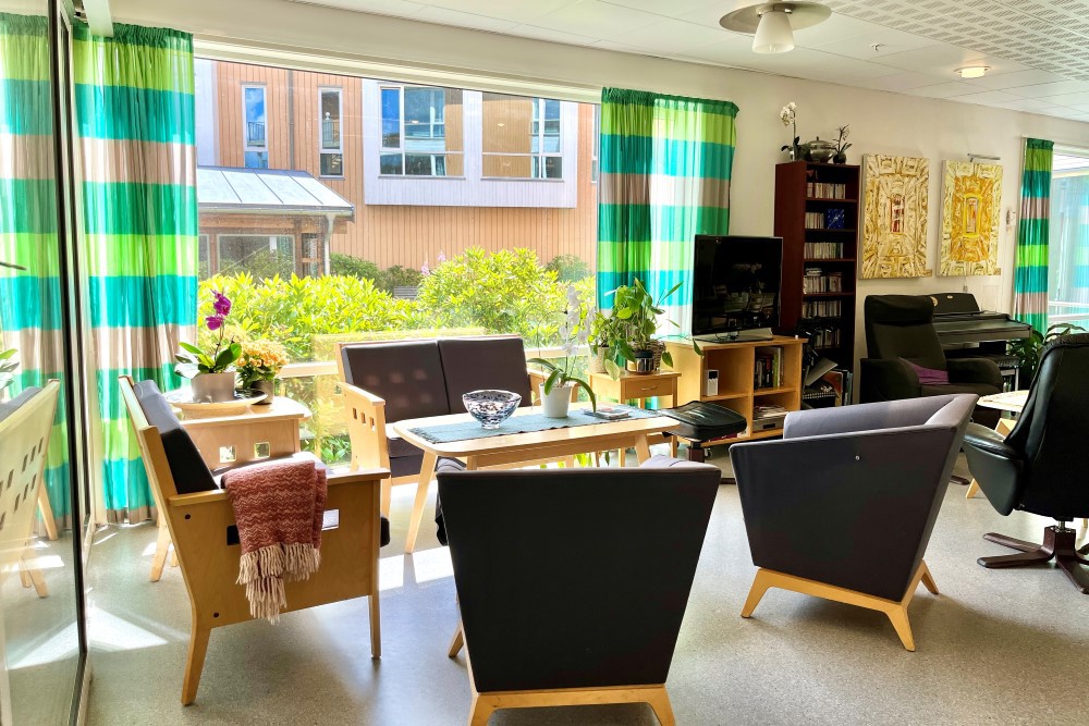 Bildet viser en koselig krok med stoler og kunst på veggene, nede i første etasje med hagen like utenfor.