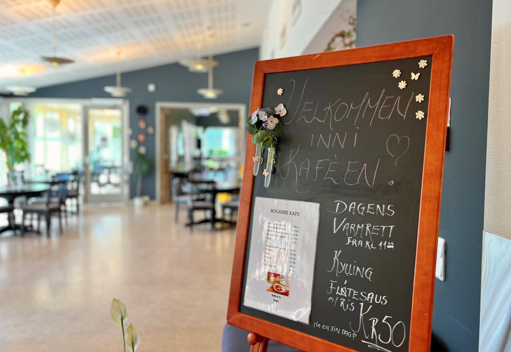 Vi et skilt som står i inngangen til kafeen, som ønsker gjestene velkommen inn.