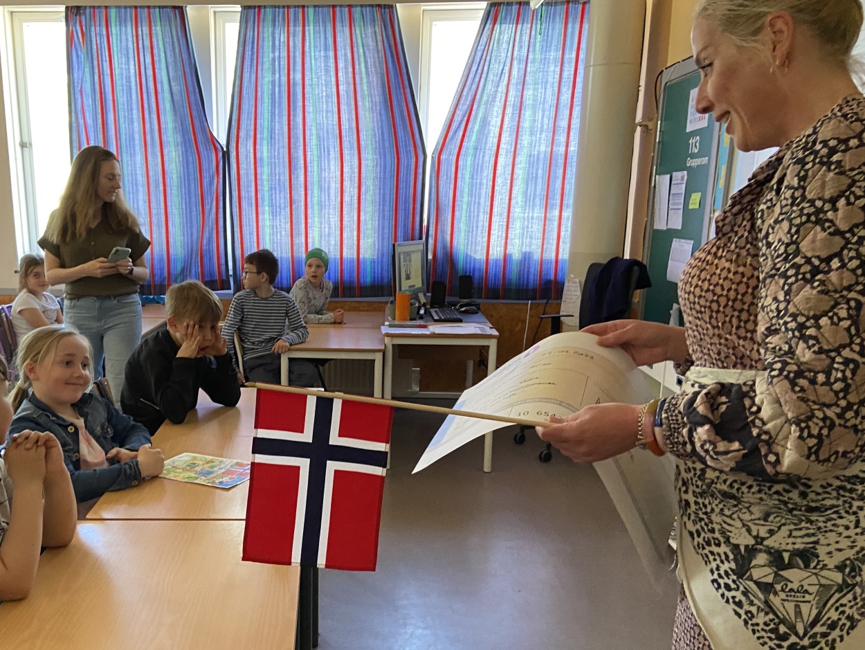 Leder i 17. mai-komiteen overrasket klasse 3A på Vaulen skole fredag. Vinneren av tegnekonkurransen, Lykke Larsen Nybø, fikk overrakt premiesjekk (ispenger?) på 1000 kroner fra komiteen. 