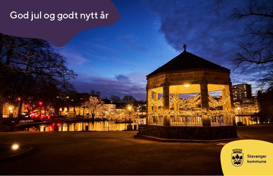 Fra musikkpavljongen i parken, i en blåmørk vinterkveld med masse julelys . Tekst på bildet: "God jul og godt nyttår. Stavanger kommune"