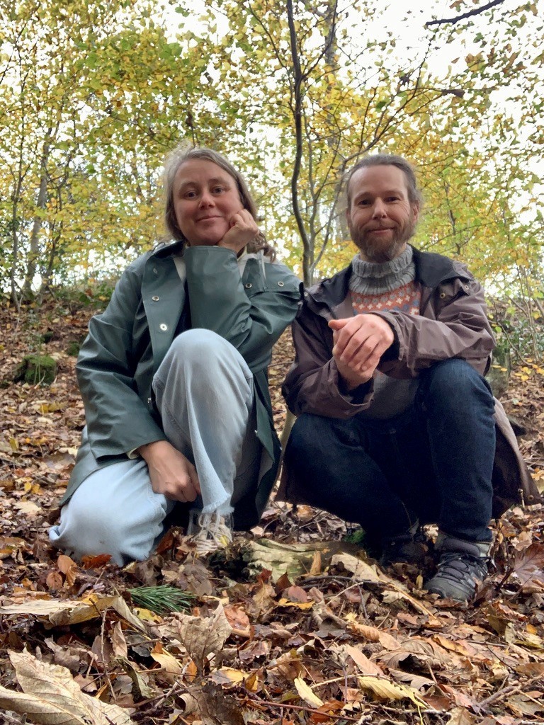 Kunstnerne Kamilla Skrinde og Kristen Rønnevik sitter på huk i skogen.