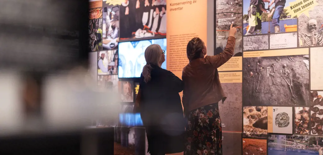 Stavanger domkirke er bygget over mange år, og i flere perioder. Kirken har også vært reparert nesten kontinuerlig, og restaurert i flere omganger i løpet av sine 900 år. Foto: Elisabeth Tønnessen. Katedralens hemmeligheter, folk ser på en utstillingsvegg på Arkeologisk museum.