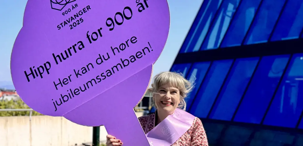 Vil du danse til rytmene av den splitter nye sambaen, bør du stille deg i nærheten av de lilla fanene, sier Stine Honoré, prosjektrådgiver i Stavanger 2025.  Jubileumssamba-skilt og  Stine Honore