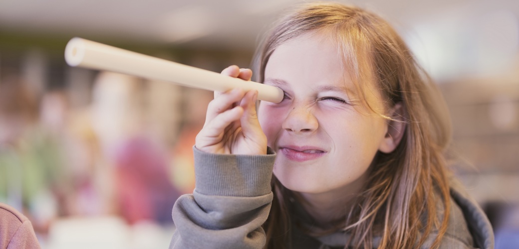 Jente kikker gjennom selvlaget kikkert. Stavanger 2025. Mindre versjon.