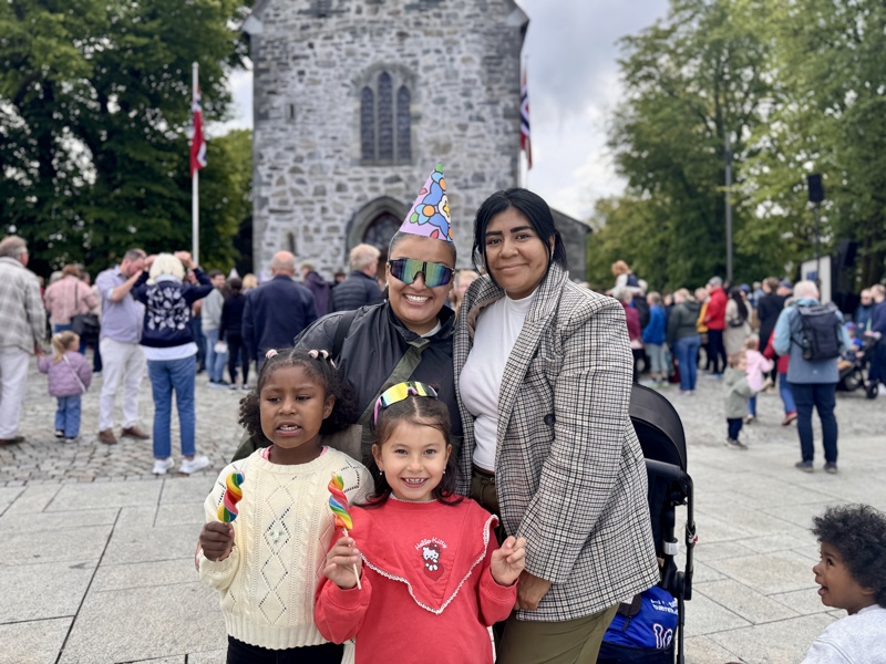 To voksne og to barn smiler til kamera foran domkirkeplassen. 