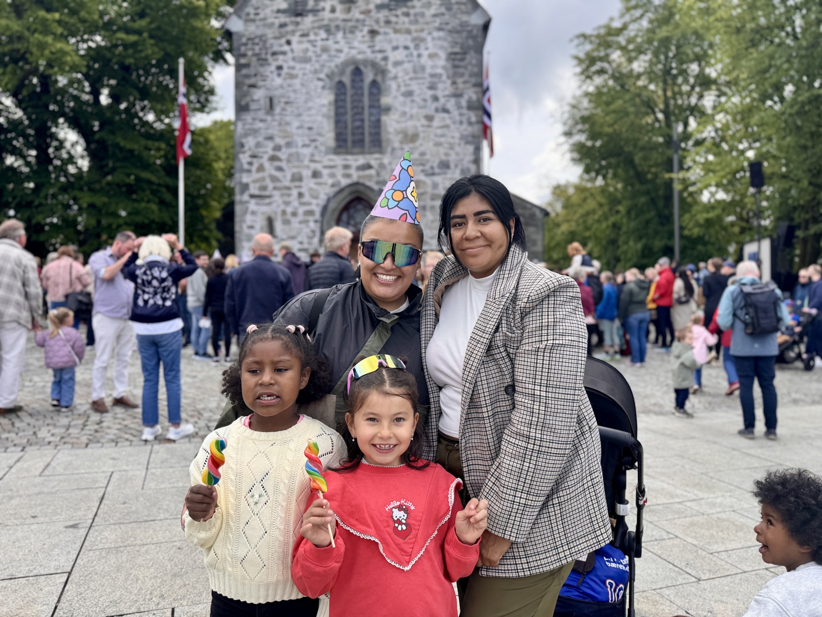 To voksne og to barn smiler til kamera foran domkirkeplassen.