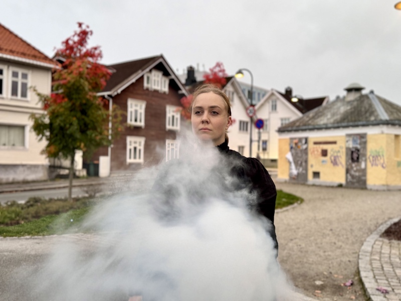 Skumle Sara Berge med røyk rundt henne. 