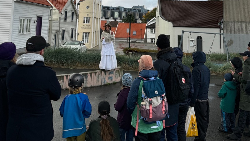 Barn og voksne i regntøy og ruskete vær. 