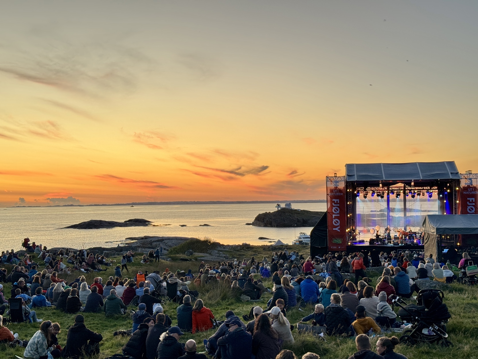 Folkehav i havgapet ser mot solnedgangen og en stor scene.