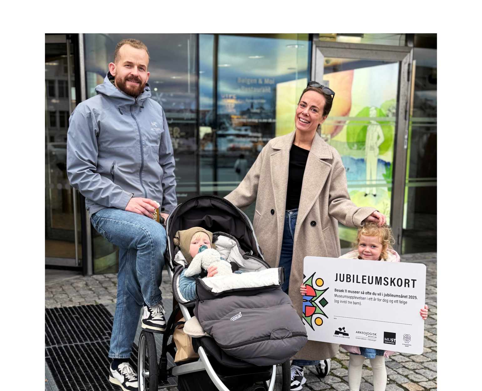 Familie på fire som poserer med et stort jubileumskort.