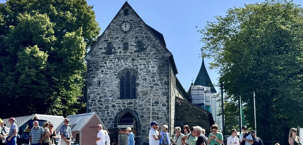 Domkirken i sommersol med masse folk foran inngangspartiet.