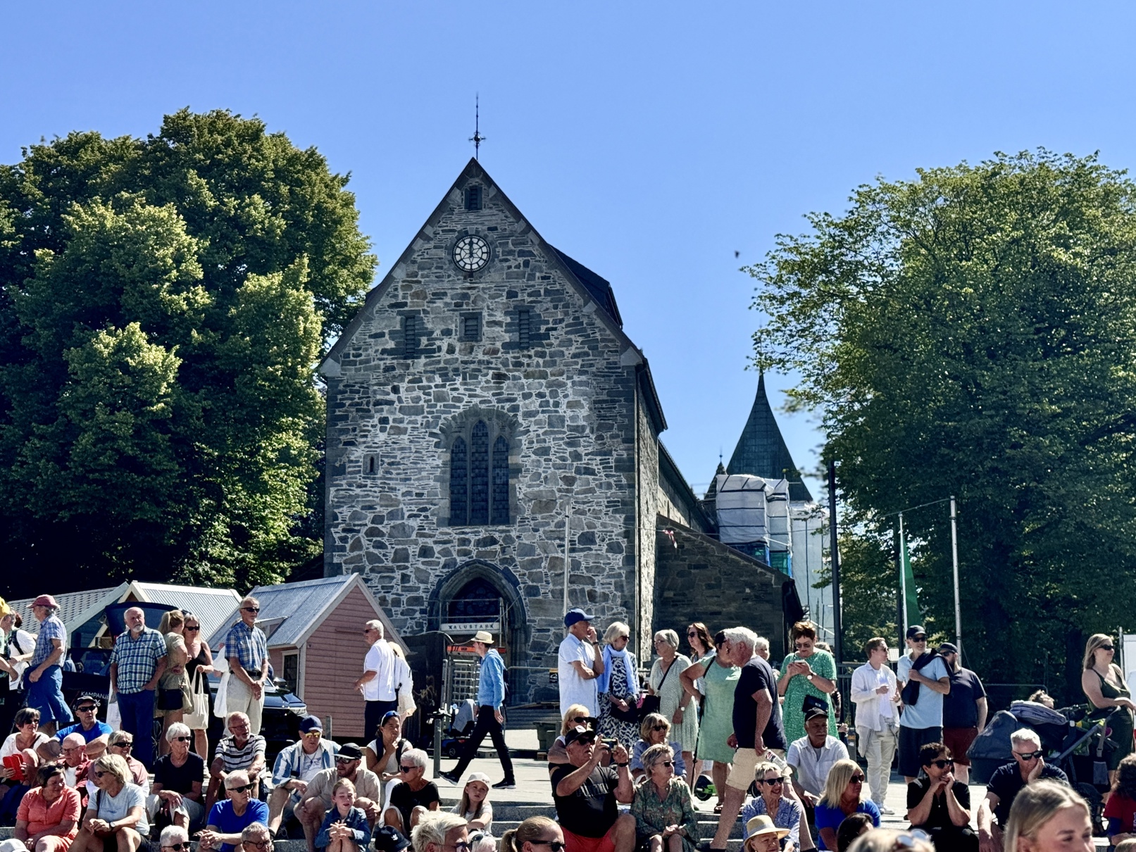 Domkirken i sommersol med masse folk foran inngangspartiet.