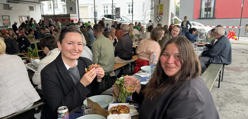 (F.v.) Sandra Vaka og Livie Johansen storkoste seg med blant annet burger fra Hekkan.  To venninner sitter på langbord og spiser middag på Blåsenborg.