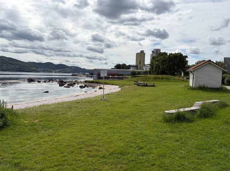 Skilt på Forusstranda. Mølla og siloen i Sandnes i bakgrunnen.