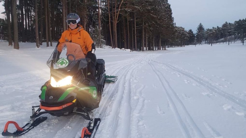 Snøscooter kjører opp skispor. Foto: Norsk folkehjelp
