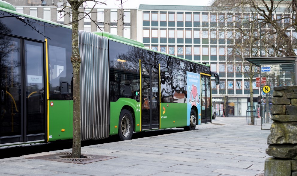 Bildet viser en grønn bybuss fra Kolumbus som står å en holdeplass ved siden av Breiavatnet.
